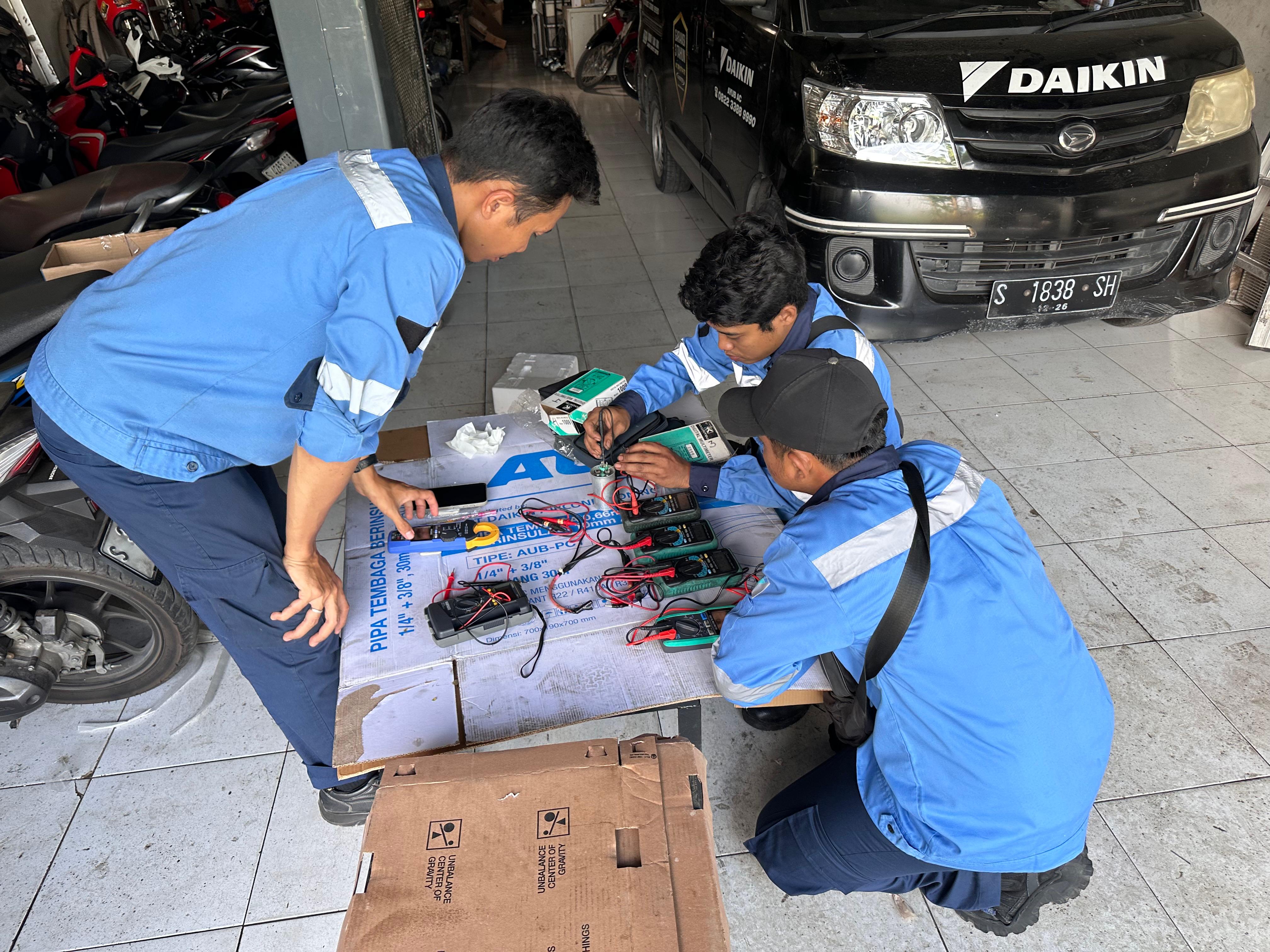 Tim teknisi menguji komponen AC di workshop