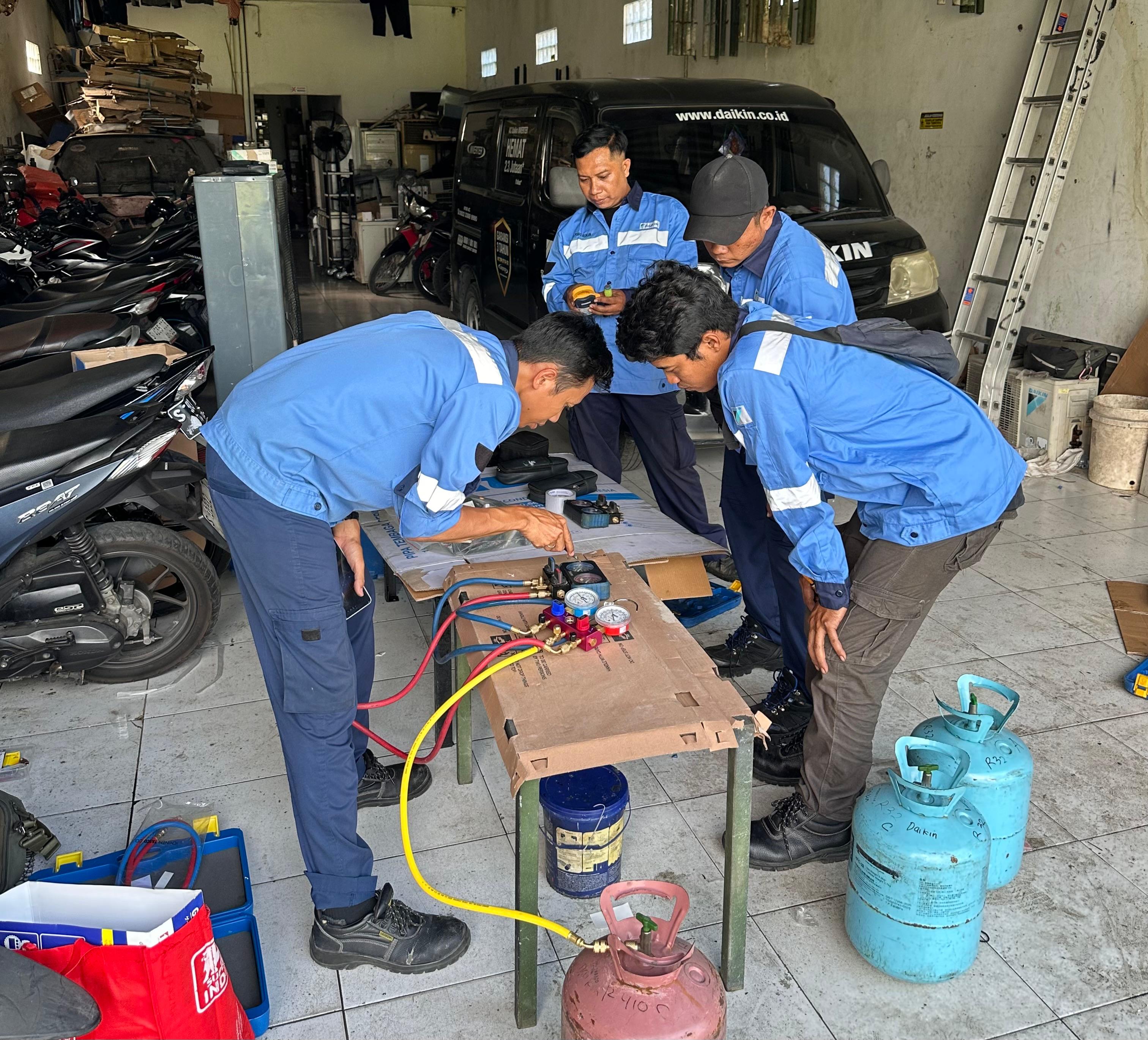 Teknisi mengisi refrigeran dengan manifold gauge